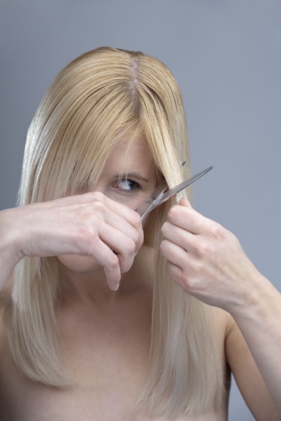 Woman cutting bangs, studio shot. 
Photo : Mark de Leeuw