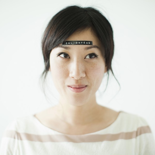 Portrait of young woman with word 'enlightenment' on forehead, studio shot. 
Photo : Jessica