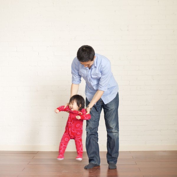 Father helping baby girl (12-17 months) with her first steps. 
Photo: Jessica Peterson