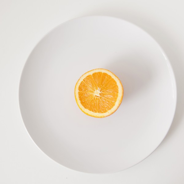 Half of orange on plate, studio shot. 
Photo : Jessica Peterson