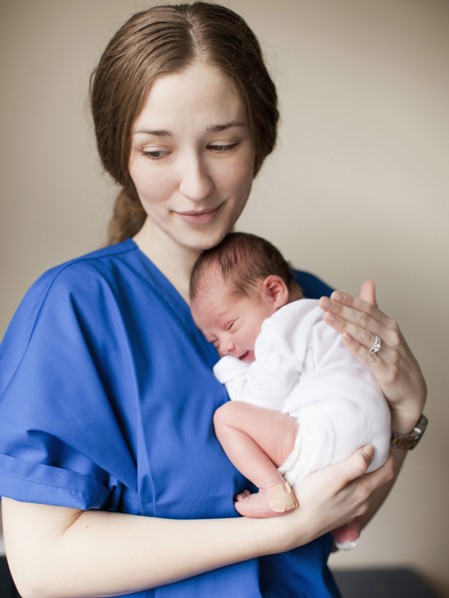 Portrait of young female nurse holding baby boy (2-5 months). 
Photo : Jessica Peterson
