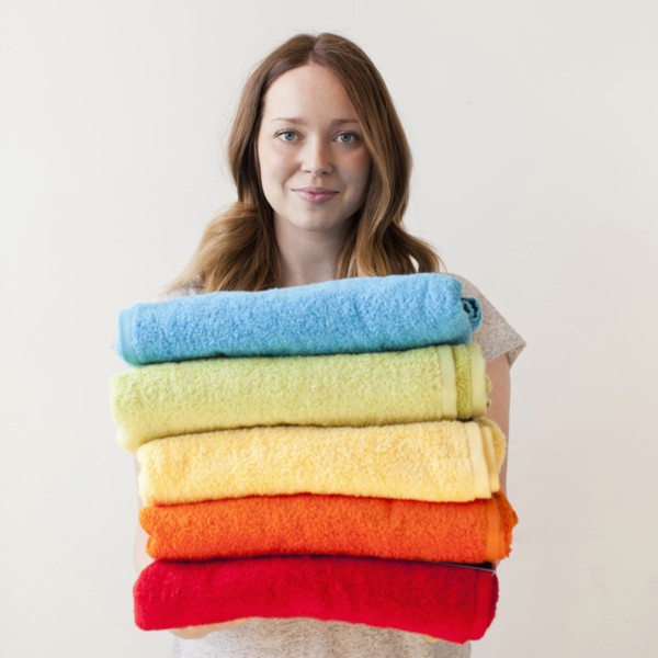 Young woman holding stack of multi-coloured towels. 
Photo: Jessica Peterson