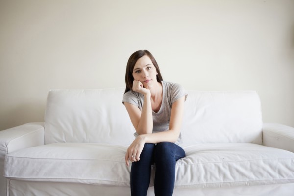 Bored young woman sitting on bed. 
Photo: Jessica Peterson