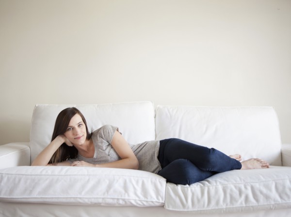 Happy young woman reclining on bed. 
Photo: Jessica Peterson