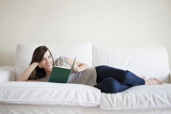 Young woman reclining on bed, reading book. 
Photo: Jessica Peterson
