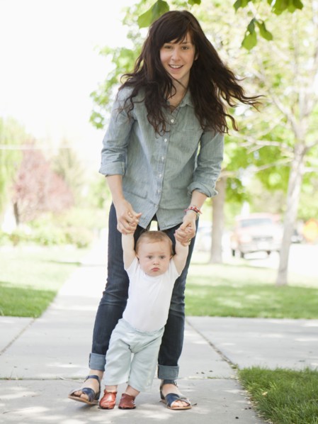 Young mother assisting baby boy (6-11 months) in his first steps. 
Photo: Jessica Peterson