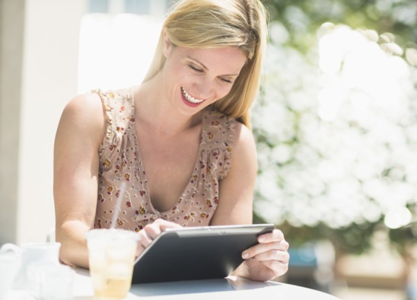 Woman using tablet pc at outdoor cafe table.