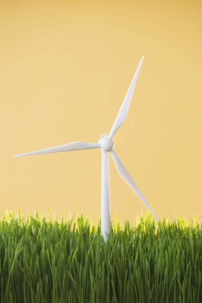 Model wind turbines in grass on yellow background.