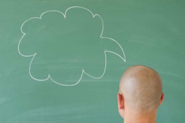 Man in front of blackboard with drawing depicting speech bubble.