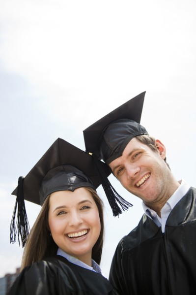 Young man and woman wearing graduation gowns. Photo : Jamie Grill
