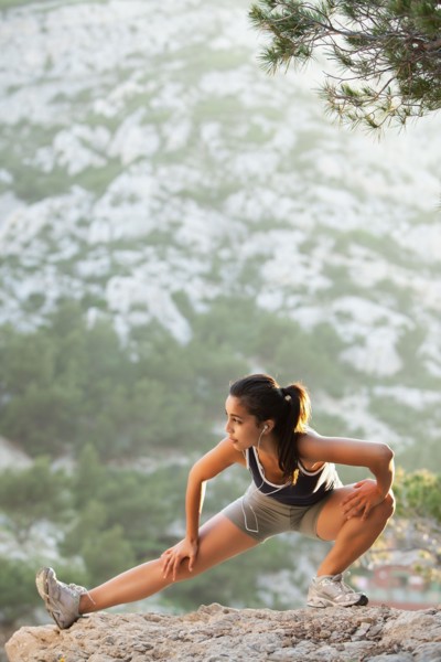 France, Marseille, Young woman stretching on cliff. Photo : Mike Kemp