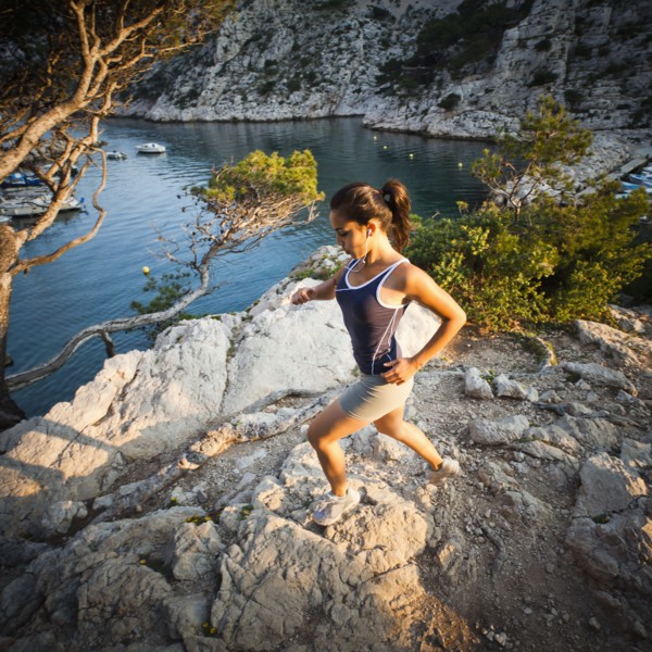 France, Marseille, Young woman jogging in rocky terrain. Photo: Mike Kemp