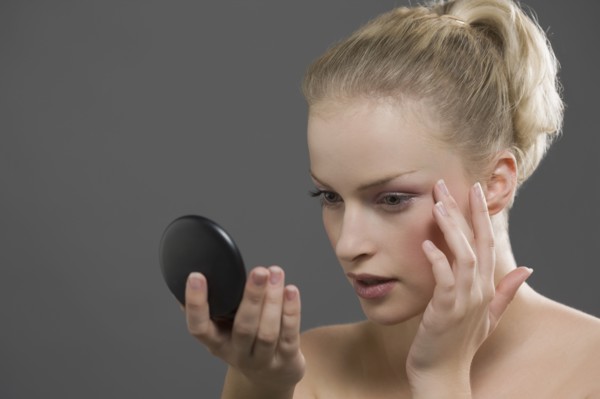 Beauty portrait of woman using powder compact. Photo : Jan Scherders