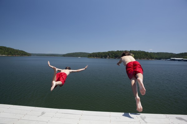 USA, Arkansas, Murfreesboro, Two brothers (8-9, 12-13) jumping into water. Photo : King Lawrence