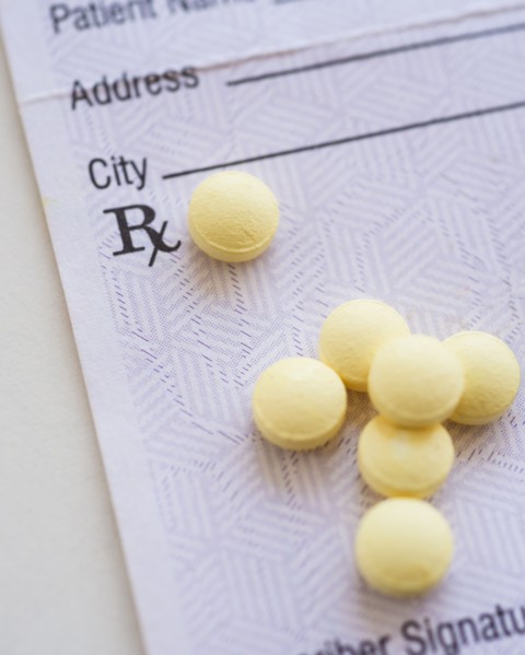 Yellow pills with prescription form, studio shot.