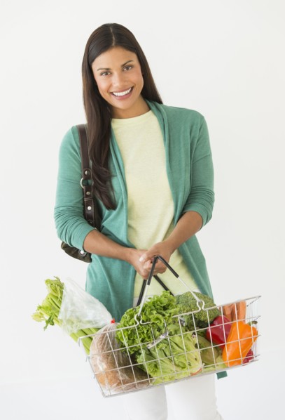 Studio shot of woman holding shopping basket with vegetables.