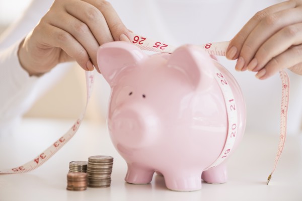 Woman measuring piggybank.