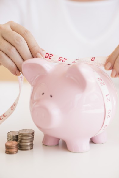 Woman measuring piggybank.