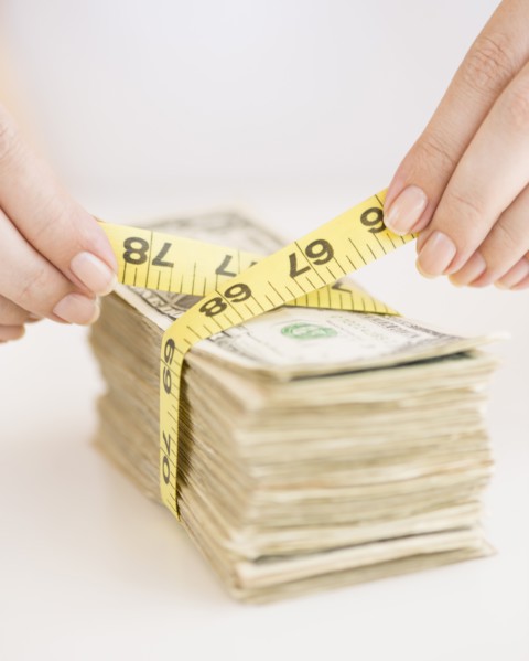 Woman measuring bunch of banknotes.