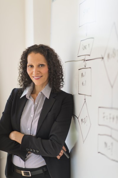 Portrait of woman standing next to whiteboard.