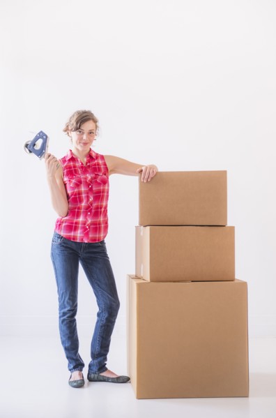 Studio shot of young woman with tape and stack of boxes. Photo: Daniel Grill