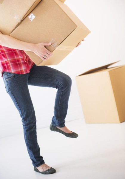 Studio shot of young woman carrying stack of boxes, low section. Photo : Daniel Grill