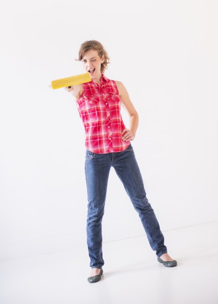 Studio shot of young woman holding paint roller. Photo : Daniel Grill
