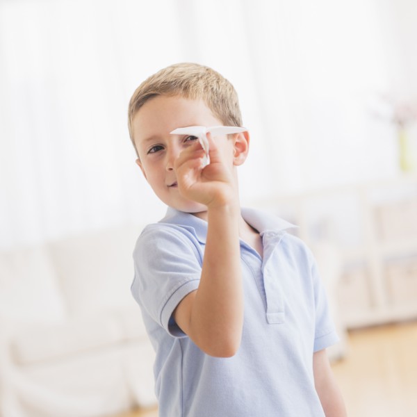 Young boy (6-7) playing with paper plane. Photo : Daniel Grill