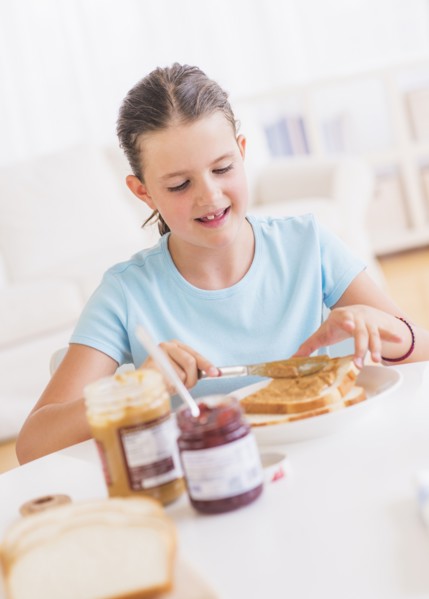 Happy young girl (8-9) having breakfast. Photo : Daniel Grill