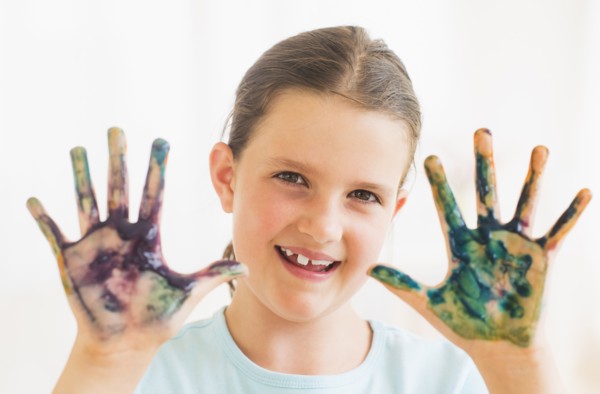 Young girl (8-9) showing hands stained with paint. Photo : Daniel Grill