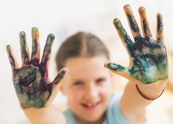 Young girl (8-9) showing hands stained with paint. Photo : Daniel Grill