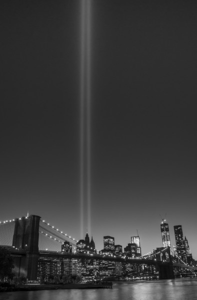 View over Hudson River towards Manhattan with September 11th memorial lights and Brooklyn Bridge.