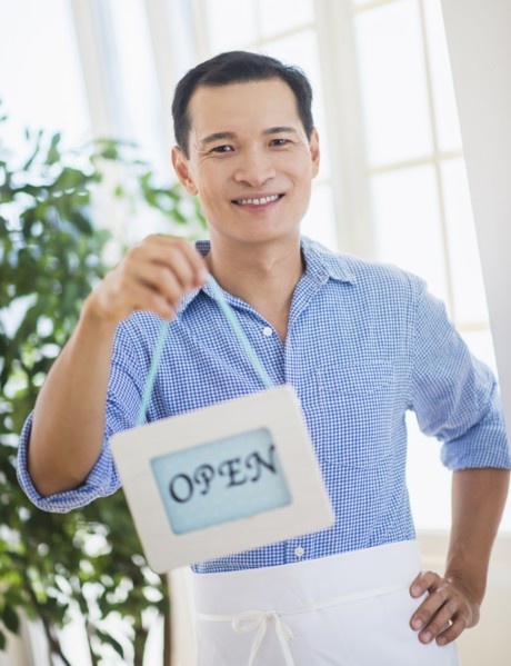 Mid adult waiter holding open sign. Photo : Daniel Grill