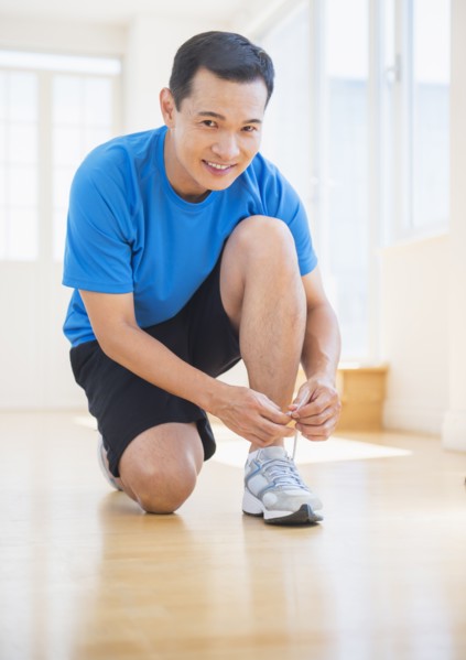 Mid adult man lacing his running shoes. Photo : Daniel Grill