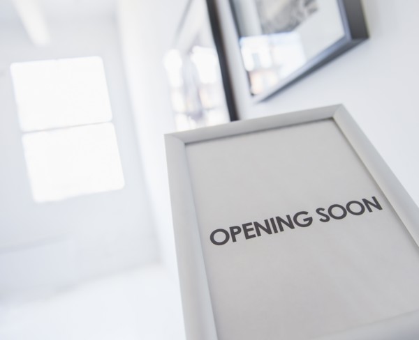 Opening sign with pictures on white wall in background. Photo : Daniel Grill