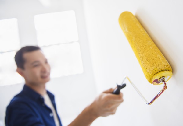 Man painting wall with painting roll. Photo : Daniel Grill