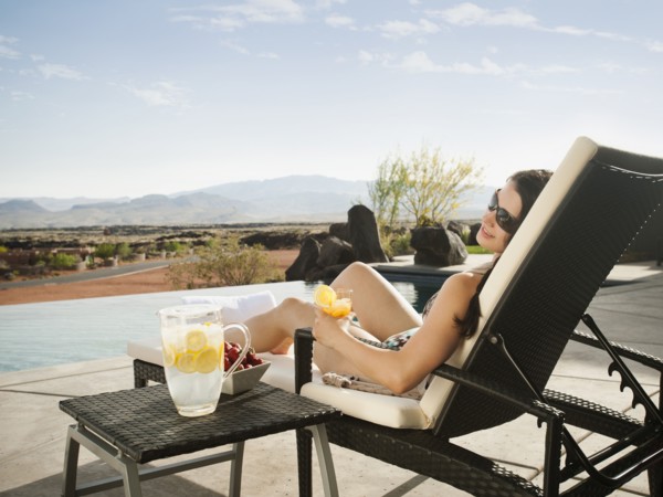 Young attractive woman enjoying cocktail by swimming pool.