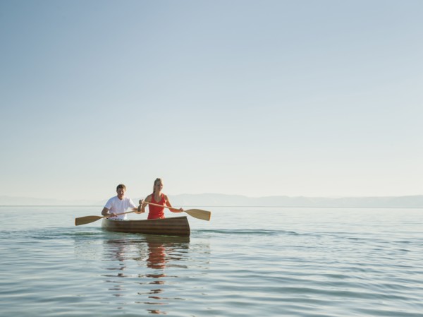 Portrait of two young people paddling canoe.