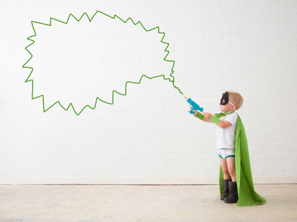 Studio shot, Portrait of boy (2-5 years) wearing green cape and holding his toy gun. Photo :