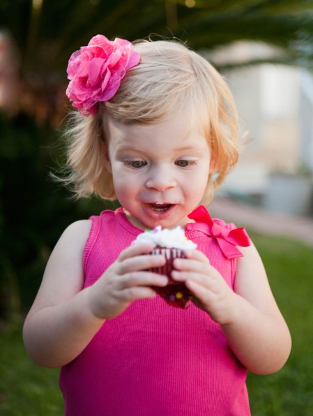 Girl with blong hair looking at cupcake. Photo : Jessica Peterson