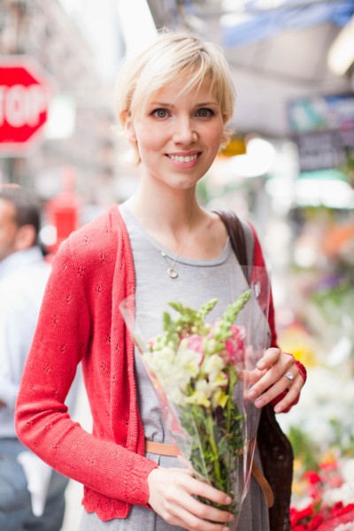 Portrait of smiling woman holding bunch of flowers. Photo : Jessica Peterson