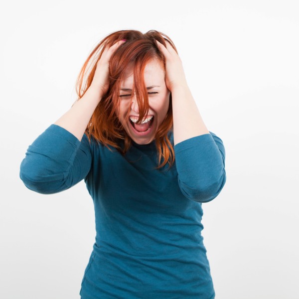 Studio shot, Portrait of woman holding her head and screaming. Photo: Jessica Peterson