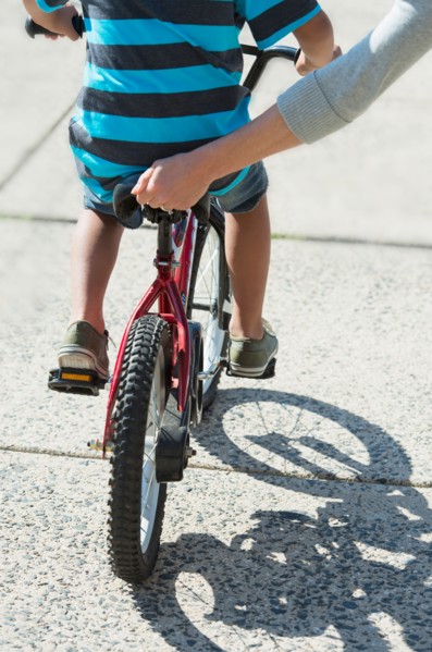 Mother helping boy (6-7) ride bicycle.