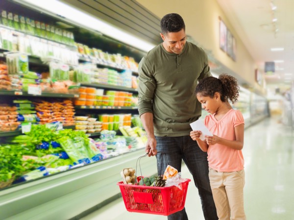 Father with daughter (6-7) shopping in supermarket.