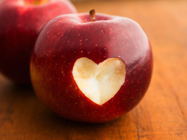 Close up of apple with missing bite in heart shape, studio shot.