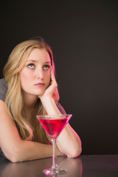 Young woman drinking martini and contemplating