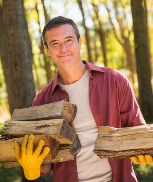 Portrait of Man holding armful of logs