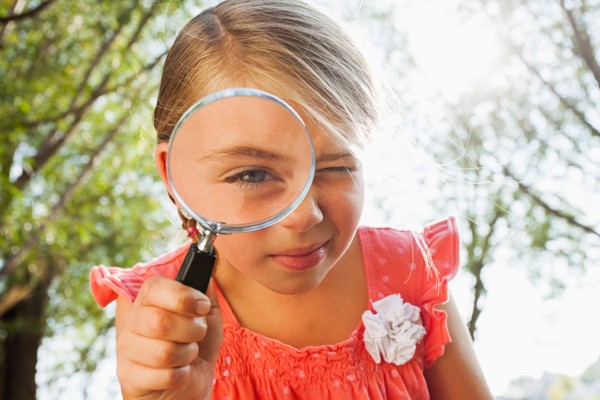 Little girl (6-7) looking through magnifying glass