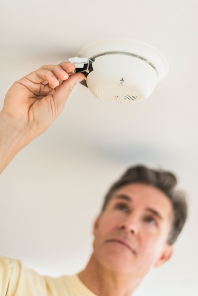 Man changing battery in smoke alarm.