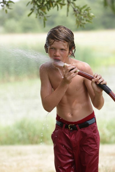 Boy (10-11) drinking from water hose in summer. Photo: pauline st.denis